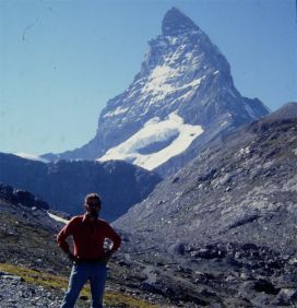 Muska Mosston standing at the base of a mountain peak