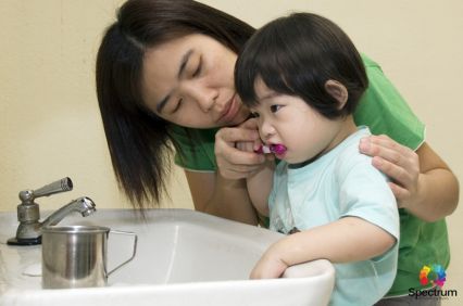 mother helping child brush teeth