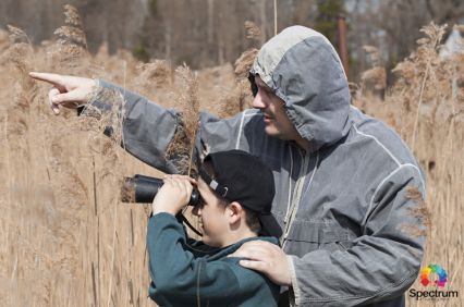 father showing son how to look through binoculars
