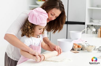 mother helping child to roll dough