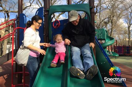 parents helping daughter go down the slide